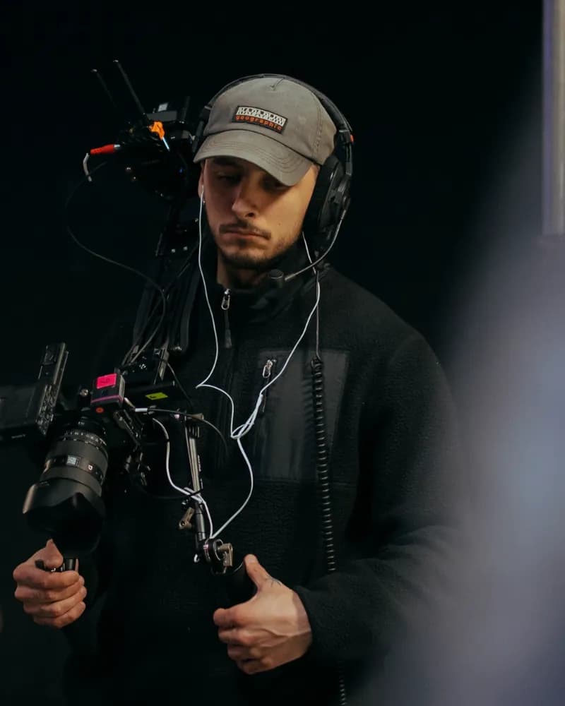 Enzo, casquette et casque sur les oreilles, caméra sur stabilisateur en main